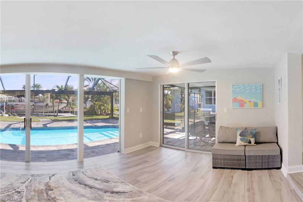 Living area with a sunroom, wood finished floors, plenty of natural light, and ceiling fan