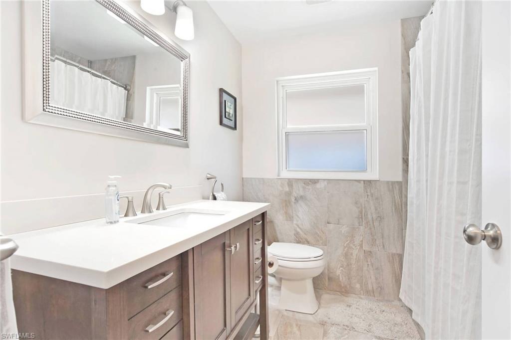 Bathroom featuring vanity, tile walls, a wainscoted wall, and a shower with curtain