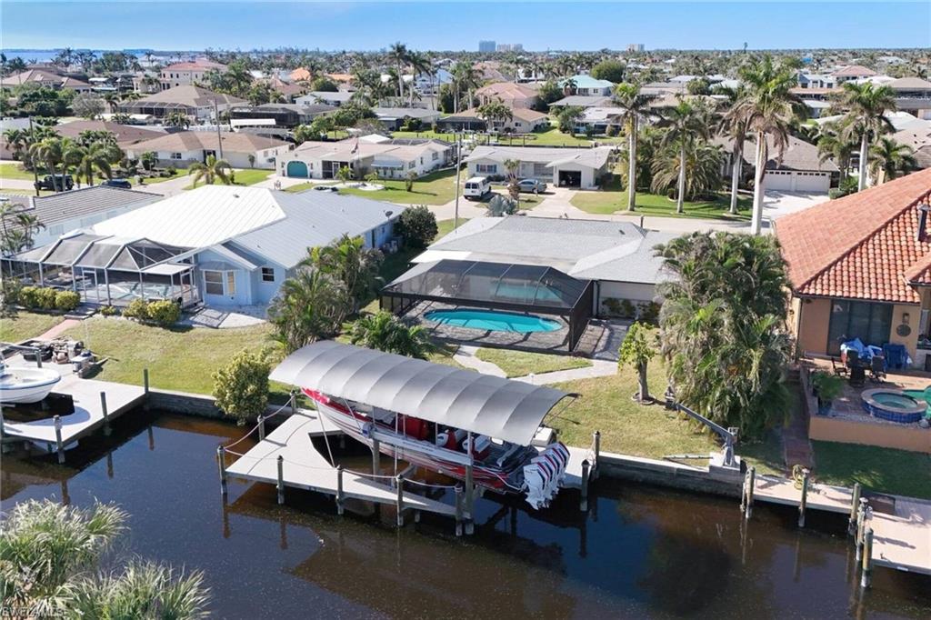 Aerial perspective of suburban area featuring a large body of water and a pool area