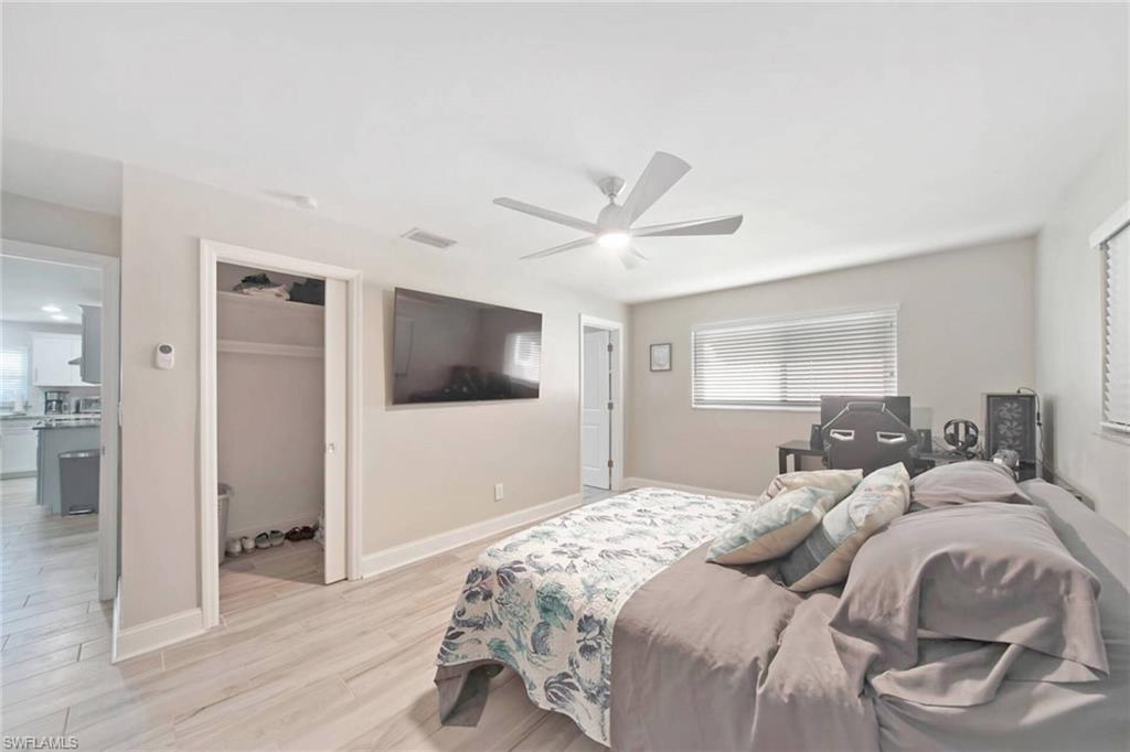Bedroom featuring light wood-style flooring, a walk in closet, ceiling fan, and multiple windows