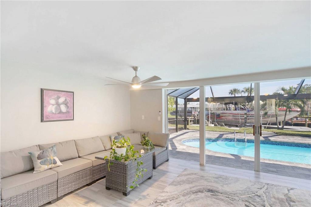 Living room featuring a sunroom, light wood finished floors, ceiling fan, and expansive windows