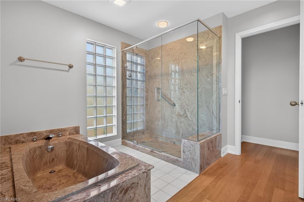 Primary Bathroom with a marble finish shower, light tile patterned floors, and a bath