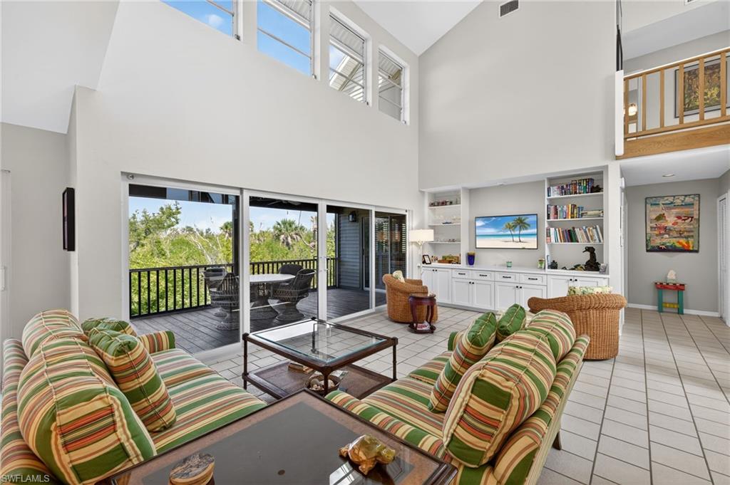 Living area featuring plenty of natural light, built in features, light tile patterned floors, and lofted ceiling