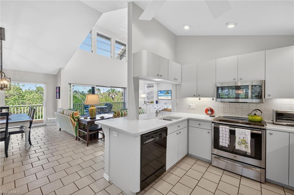Kitchen featuring tasteful backsplash, stainless steel appliances, light countertops, a peninsula, and lofted ceiling