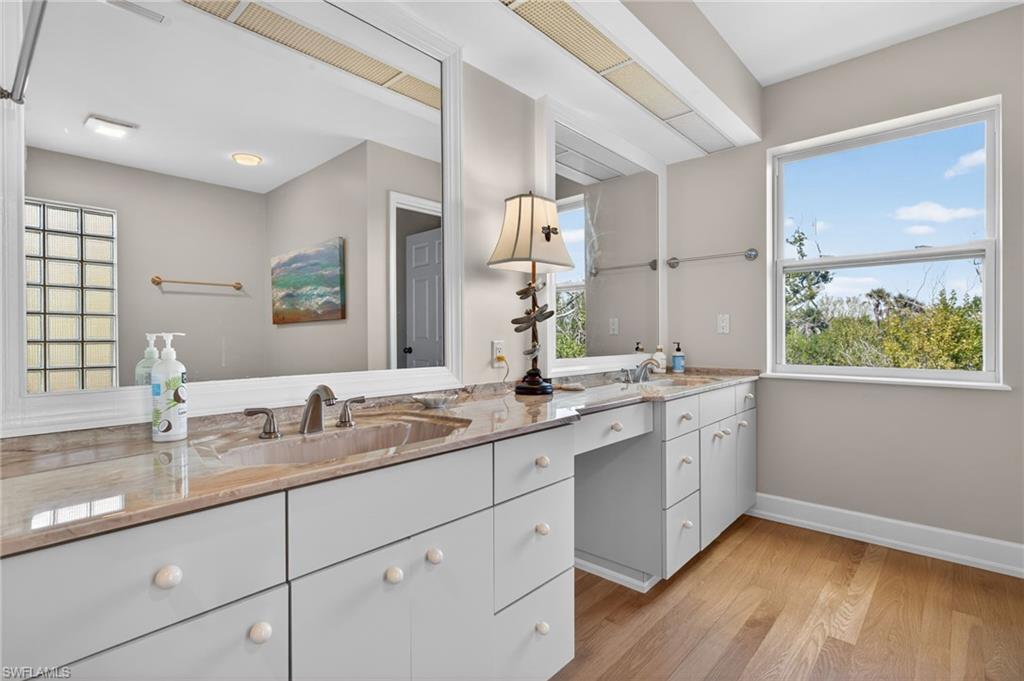 Primary Bathroom with double vanity and light wood-type flooring