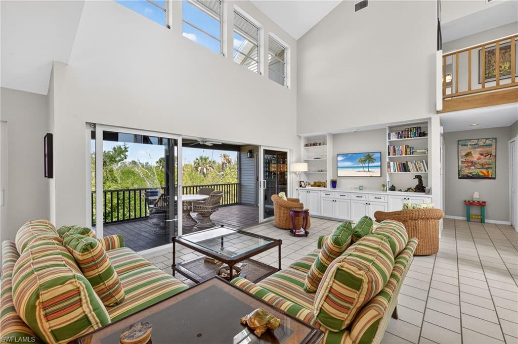 Living room with healthy amount of natural light, built in features, light tile patterned floors, and vaulted ceiling