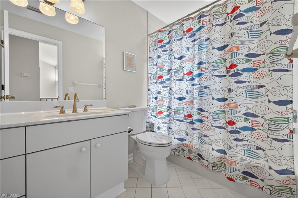 Full bathroom with vanity, light tile patterned floors, and a shower with curtain