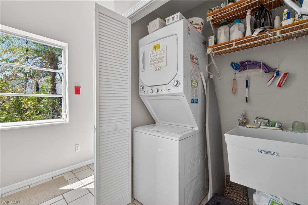 Laundry area with stacked washer and clothes dryer and light tile patterned floors