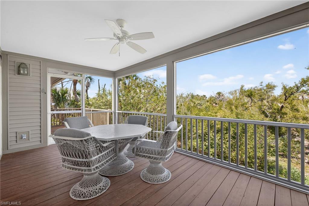 Sunroom featuring outdoor dining area, ceiling fan, and a deck