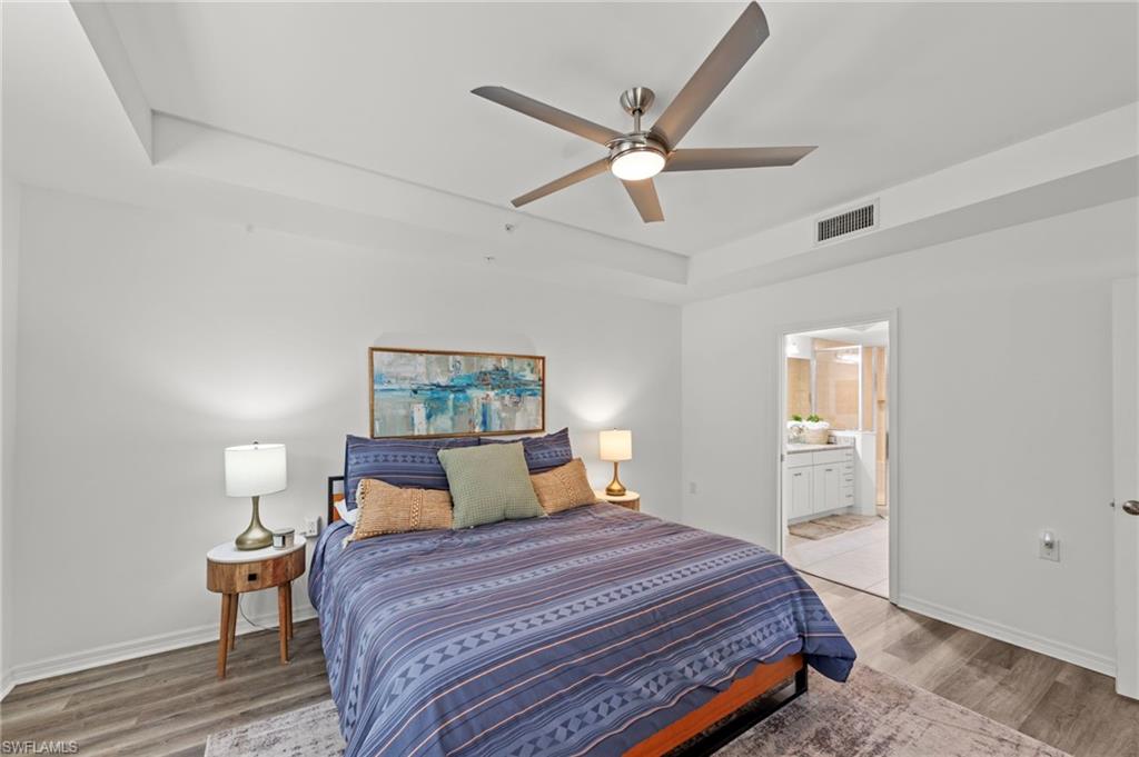 Bedroom featuring wood-look flooring, a ceiling fan, and tray ceilings