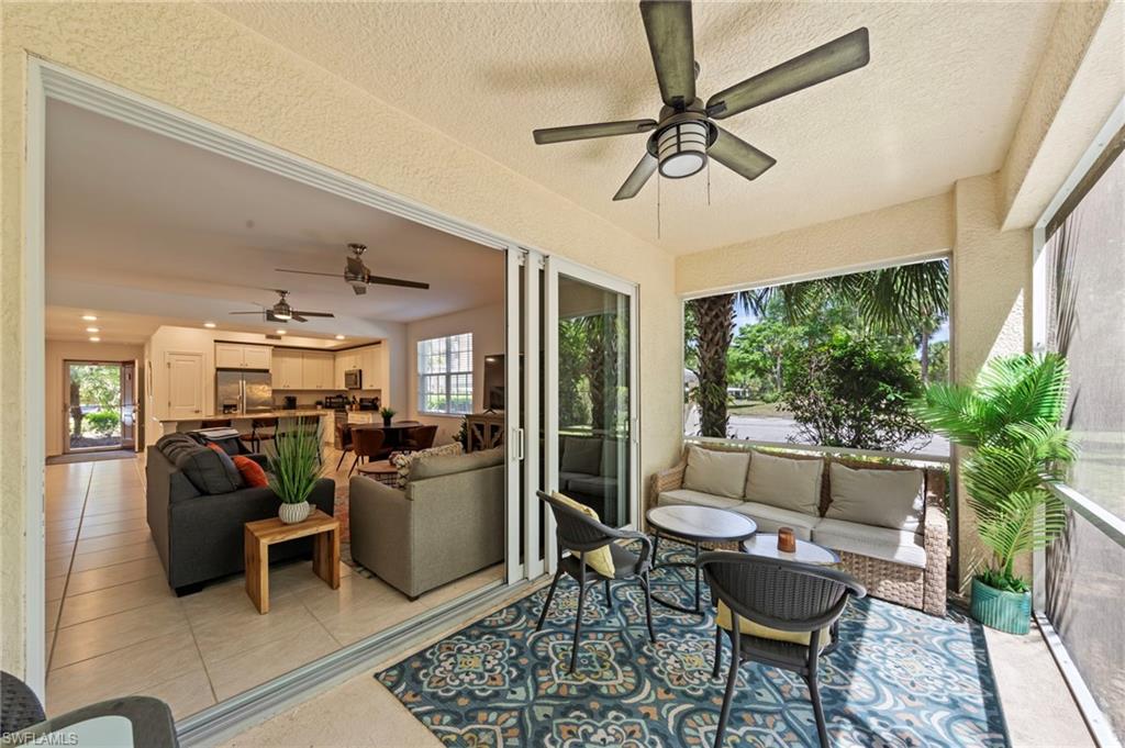 Expansive screened patio featuring a ceiling fan, tiled flooring, and views of the surrounding area, with sliding glass doors opening to the living area and kitchen