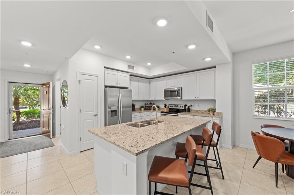 The property features a kitchen with white cabinetry, stainless steel appliances, and a granite island with an integrated sink