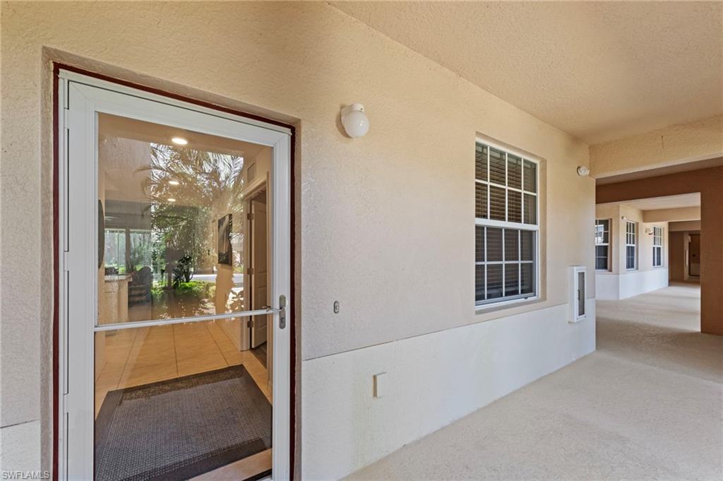 Entryway featuring a glass storm door, a window with blinds, and light-colored exterior walls