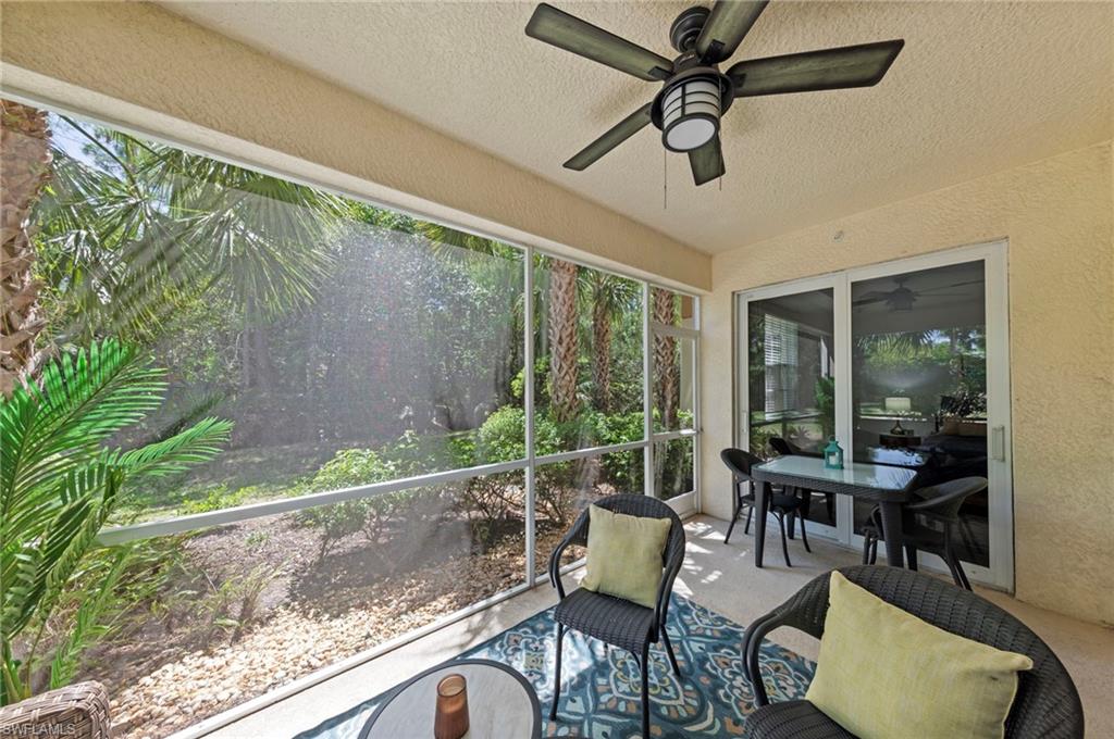 The property features a screened-in patio with a ceiling fan, offering views of surrounding palm trees and greenery