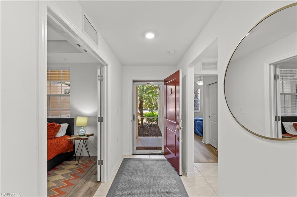 Entryway featuring a red front door, tiled flooring, and a round wall mirror