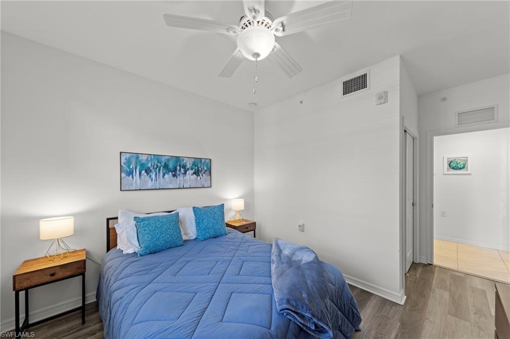 This bedroom features light wood-style flooring, a white ceiling fan, and white walls
