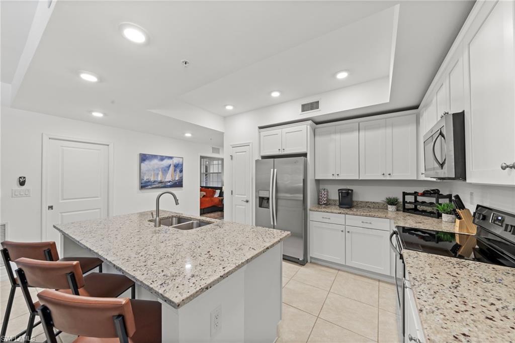The kitchen features white cabinetry, granite countertops, tile flooring, and recessed lighting