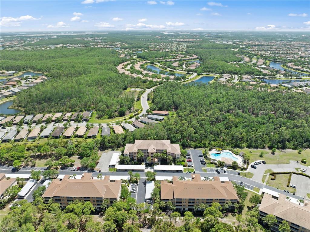 The property is located within a community featuring several residential buildings, surrounded by extensive green spaces and mature trees