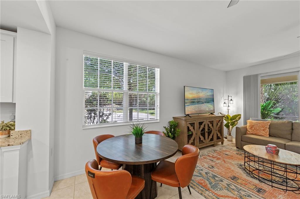 The living area features a window with blinds, tiled flooring, and views of greenery