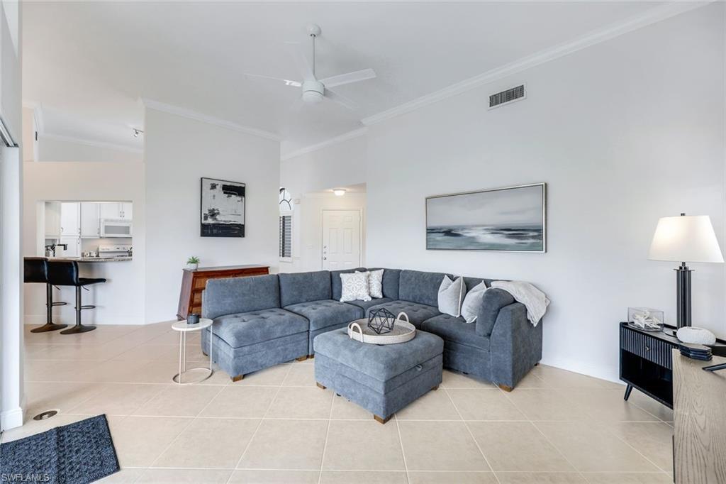 Tiled living room with ceiling fan and ornamental molding