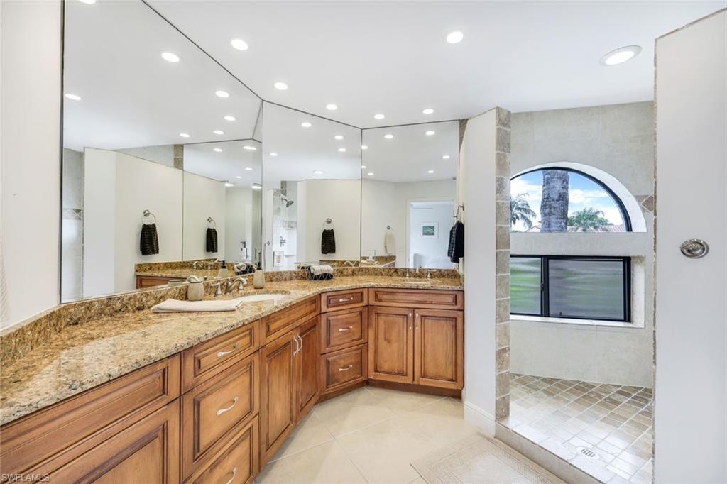 Bathroom featuring tile patterned flooring, double sink vanity, and a tile shower