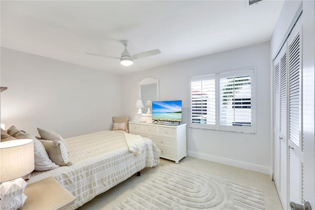 Bedroom with a closet, light tile patterned floors, and ceiling fan