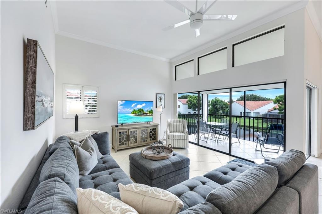Living room featuring ceiling fan, light tile patterned flooring, a wealth of natural light, and ornamental molding
