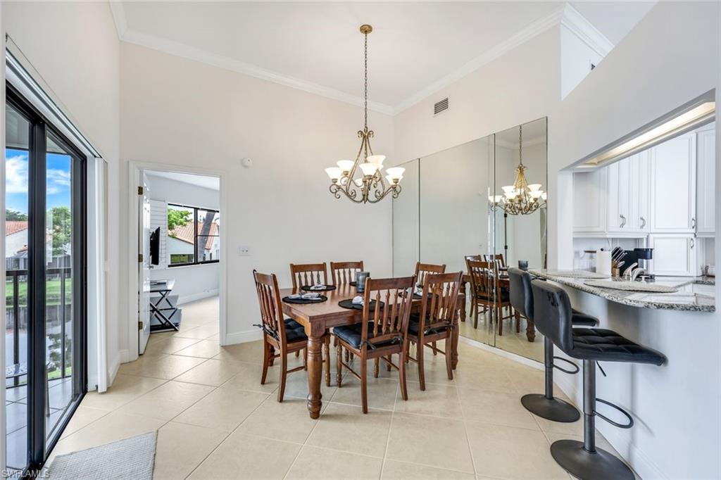 Dining space featuring ornamental molding, an inviting chandelier, light tile patterned floors, and a towering ceiling