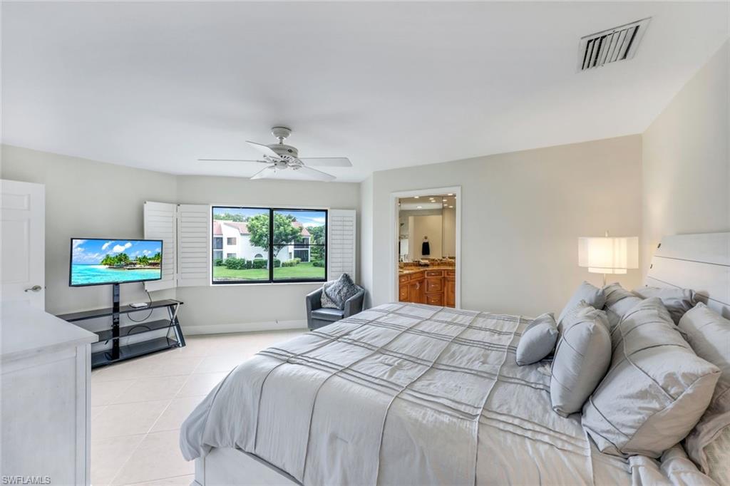 Bedroom featuring ensuite bath, ceiling fan, and light tile patterned floors