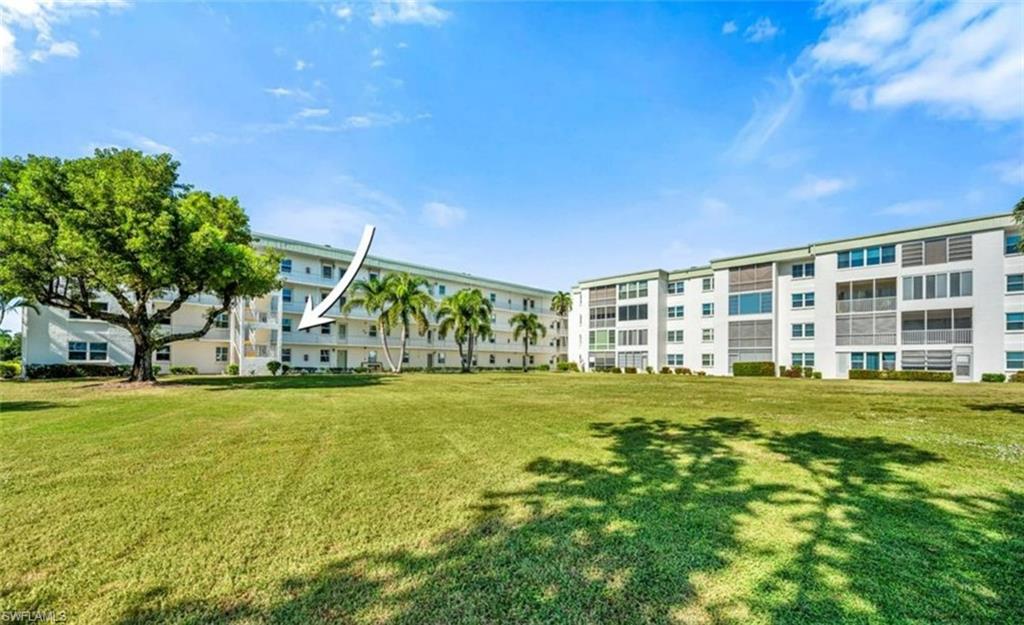 The property features a building with multiple levels overlooking a green landscape with mature trees and a paved path