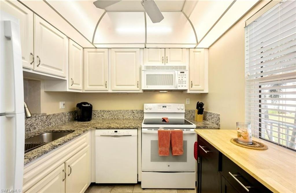 The kitchen features white cabinetry, granite countertops, and a full suite of white appliances including a refrigerator, dishwasher, and stove