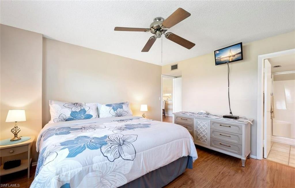 The room features wood-style flooring, a ceiling fan, and access to a bathroom with a bathtub