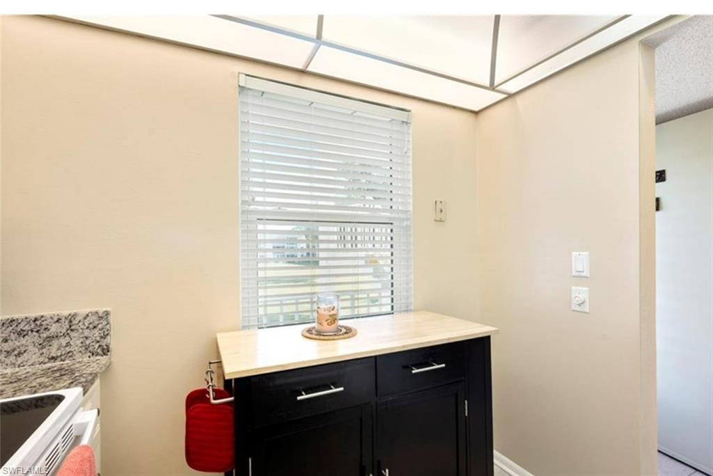 The kitchen features a window with blinds, a dark-colored cabinet with a light-colored countertop, and a built-in ceiling light fixture