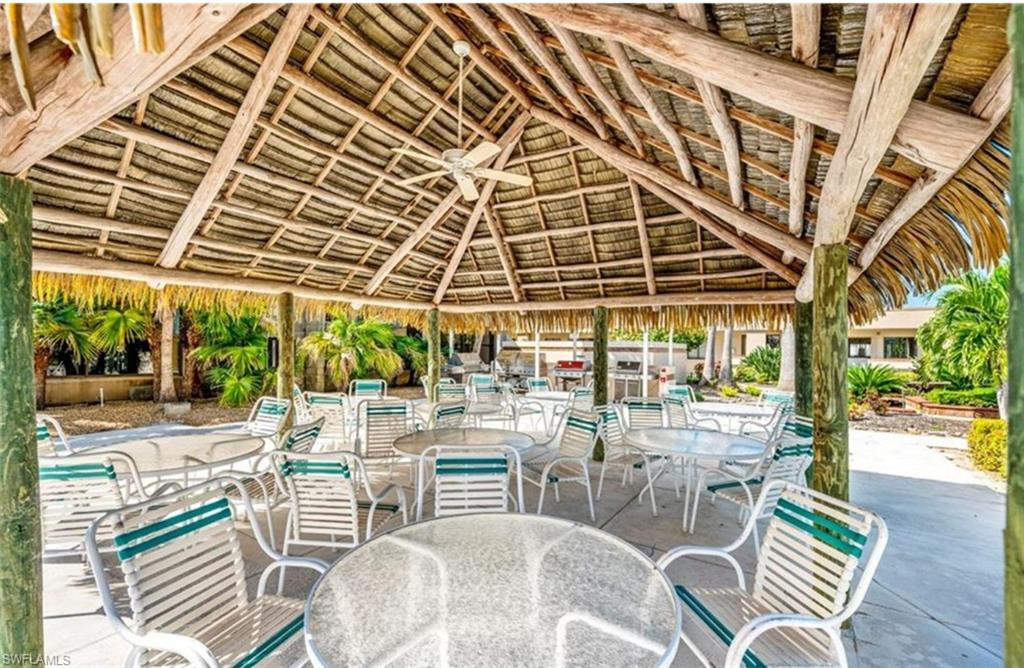 The property features an inviting outdoor covered patio space with a thatched roof, supported by robust wooden posts