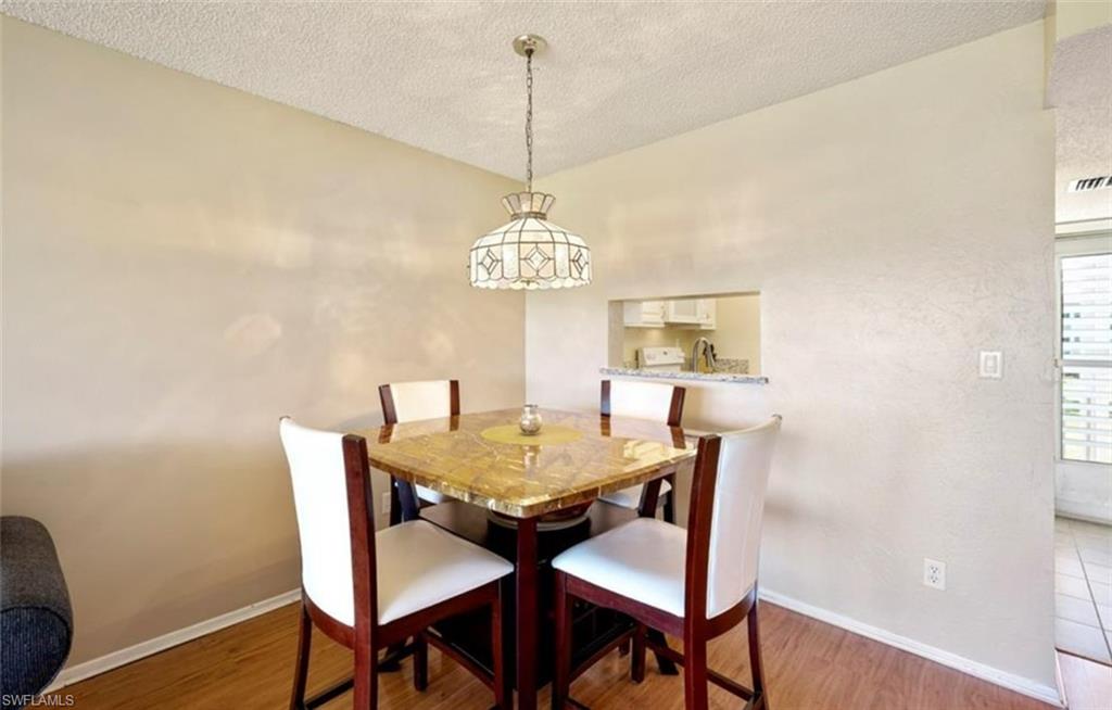Dining area featuring wood-look flooring, a pass-through window to the kitchen, and a decorative overhead light fixture