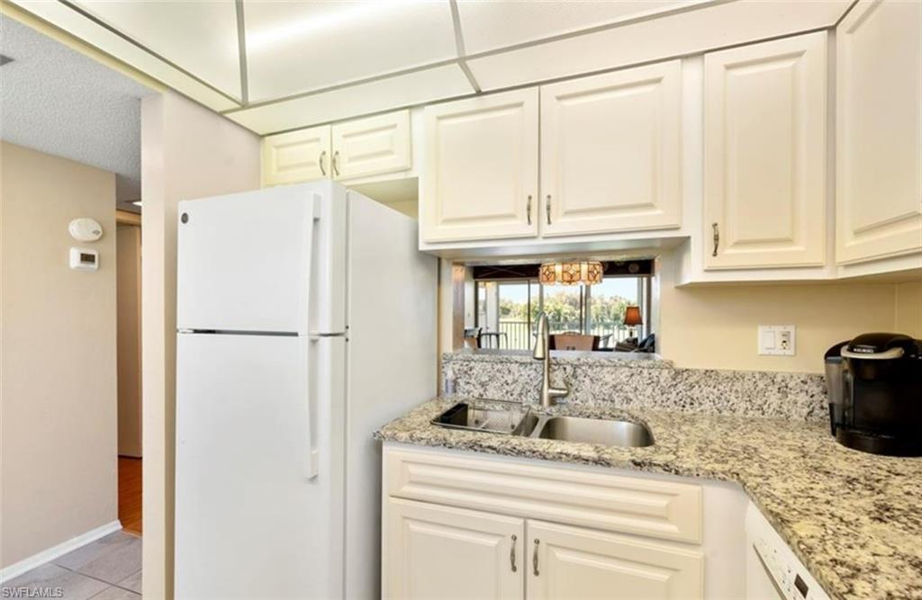 Kitchen featuring a white top-freezer refrigerator, white cabinetry, a double basin sink, and granite countertops