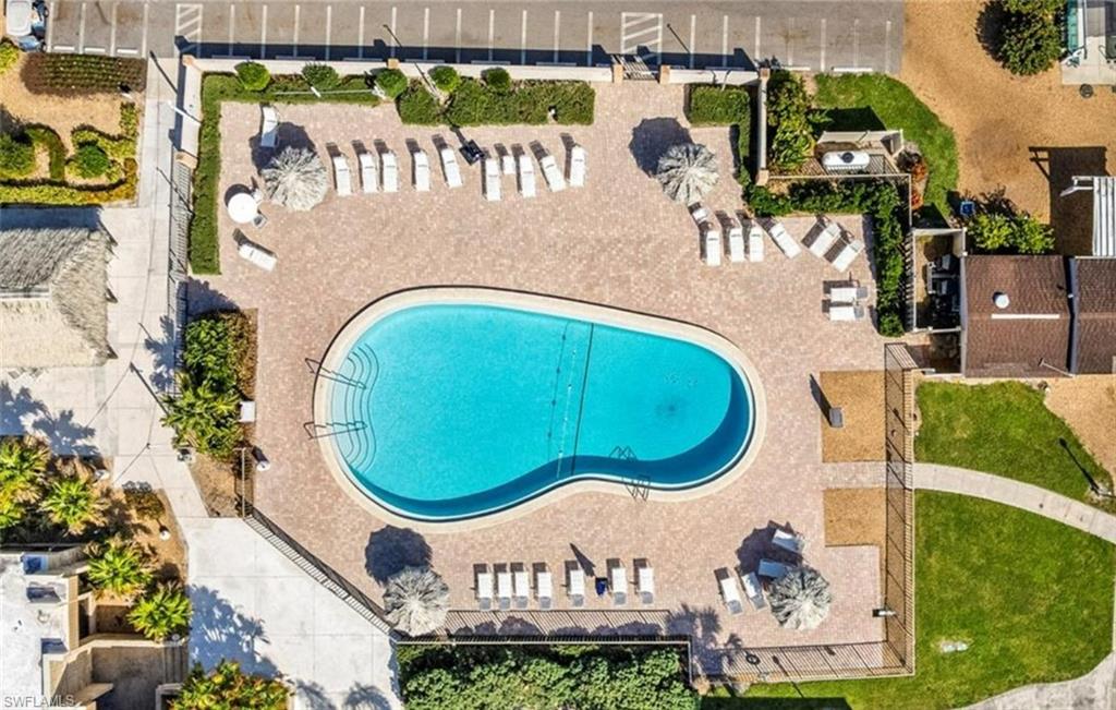 The property features an outdoor swimming pool with surrounding lounge chairs and umbrellas, set within a paved patio area