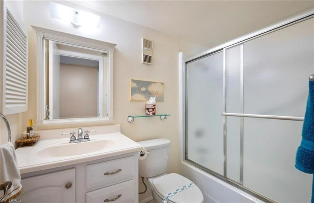 Bathroom featuring a vanity with a white countertop and sink, a mirrored medicine cabinet, and a shower with frosted glass sliding doors
