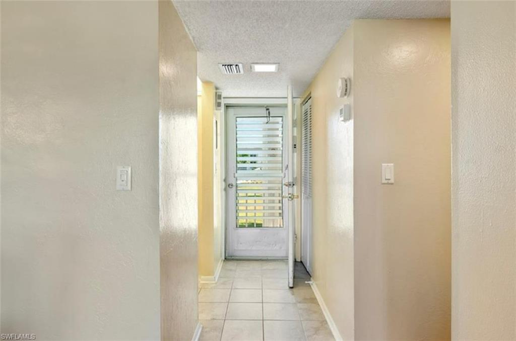 The property features a hallway with tiled flooring and a white door with louvered glass panels