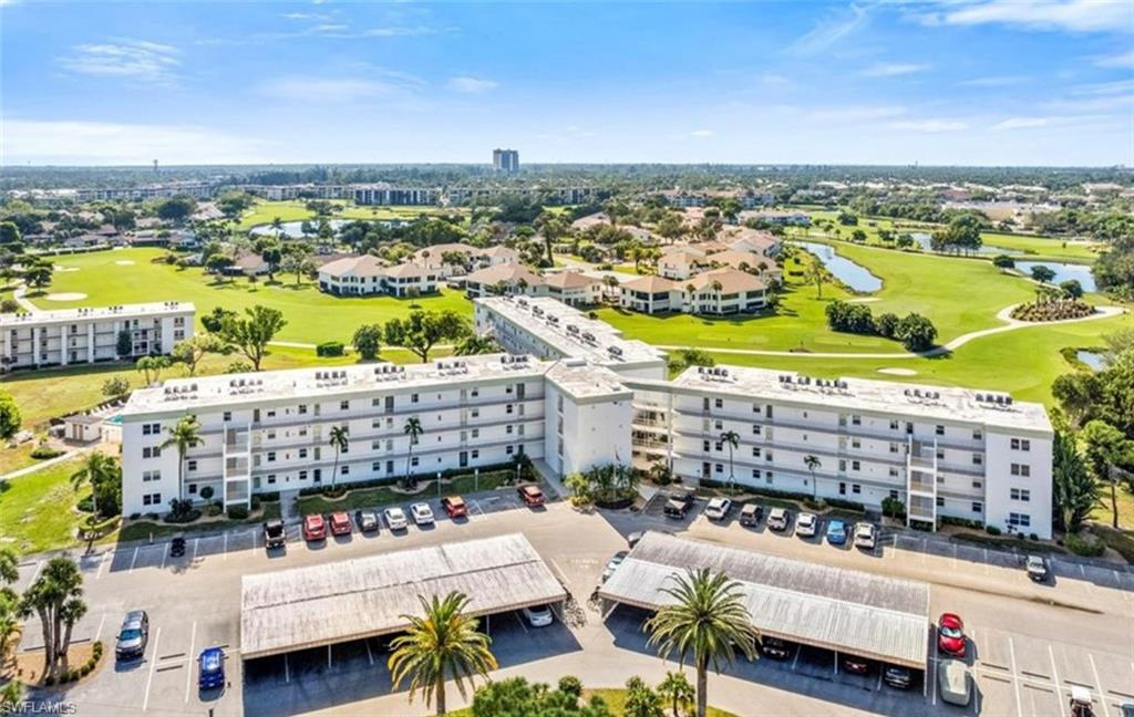 This property features a multi-story building with covered parking and a view of a golf course with water features