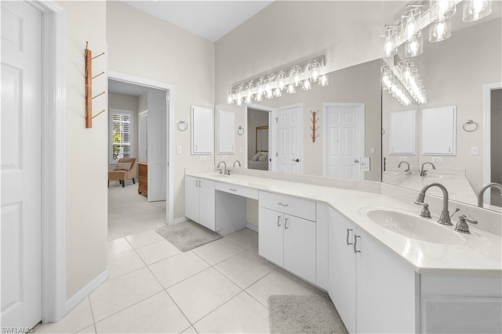 This bathroom features a double vanity with white cabinetry and light-colored countertops