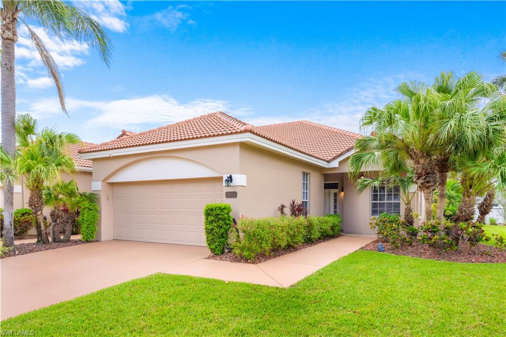 The property features a terracotta tile roof, a two-car garage, and a well-maintained lawn with mature palm trees
