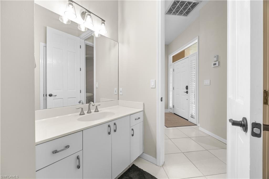 This bathroom features a spacious vanity with white cabinetry, a light-colored countertop, and a large mirror