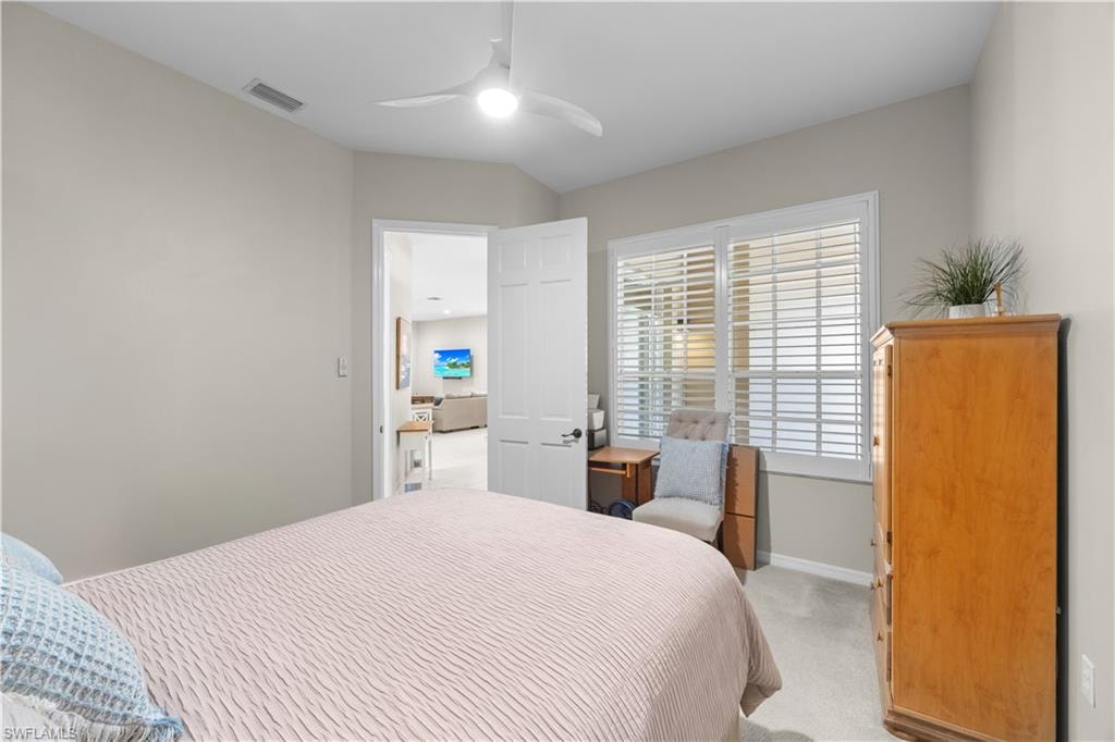 This room features carpeting, a window with plantation shutters, and a ceiling fan