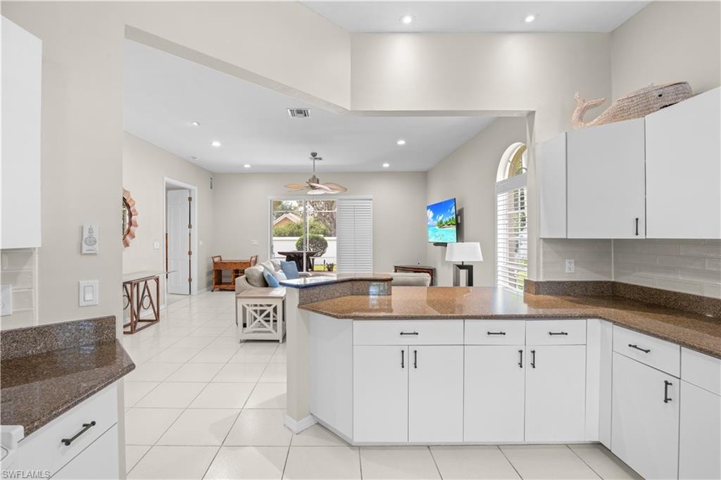 The kitchen features white cabinetry, granite countertops, and a tile backsplash, with tile flooring extending throughout the space
