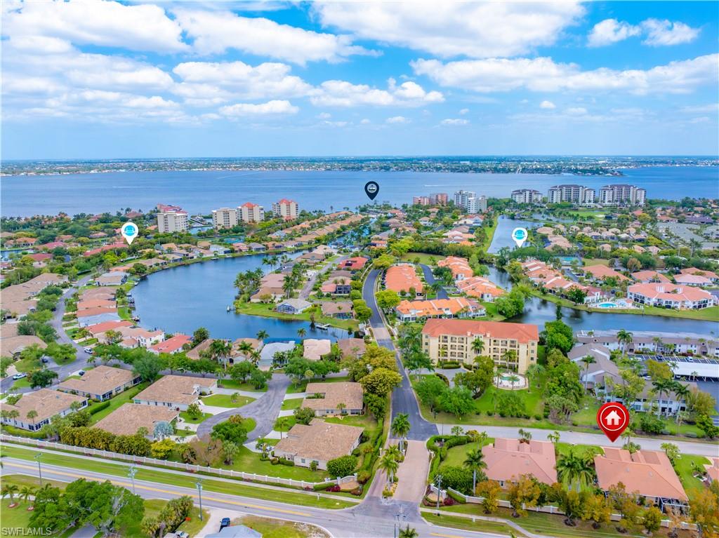 Aerial view of the property's community, featuring a large body of water, residential properties with landscaping, and a distant coastline