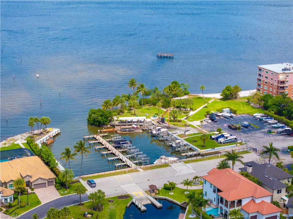 This aerial view highlights the property's proximity to a body of water with docks, a sandy beach, and lush green spaces