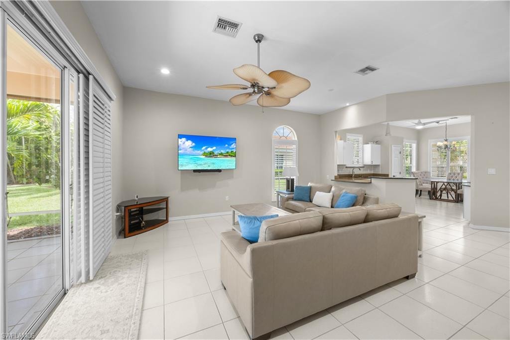 Bright living area featuring tiled flooring, a ceiling fan, and sliding glass doors leading to the outdoor space