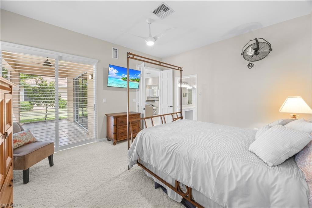 The property features a bedroom with neutral-toned walls, light-colored carpeting, a ceiling fan, and a glass sliding door that opens to an outdoor patio area