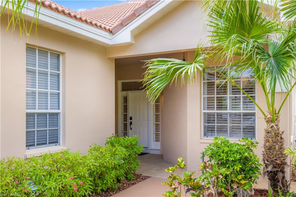 The property features an inviting entrance with a white front door, well-maintained landscaping, and a distinctive barrel tile roof